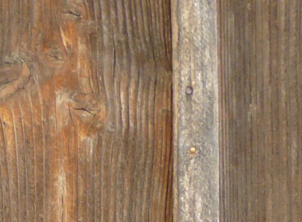 Old wood paneling with thin planks set vertically at repeating intervals.